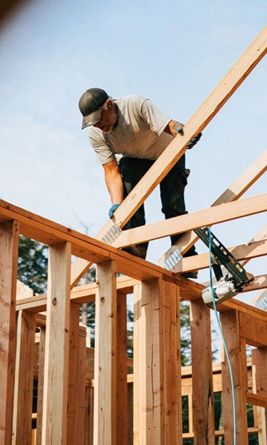 Person looking down, working on a house under construction.