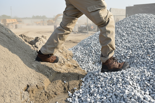 Worker in composite toe work boots standing on gravel at a construction site
