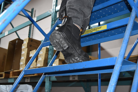 Composite toe work boots on worker climbing warehouse stairs, industrial setting