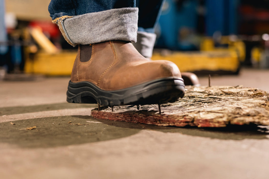 Composite toe work boot stepping safely on nails in an industrial setting