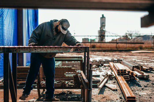 Construction worker in composite toe work boots inspecting metal beams at job site