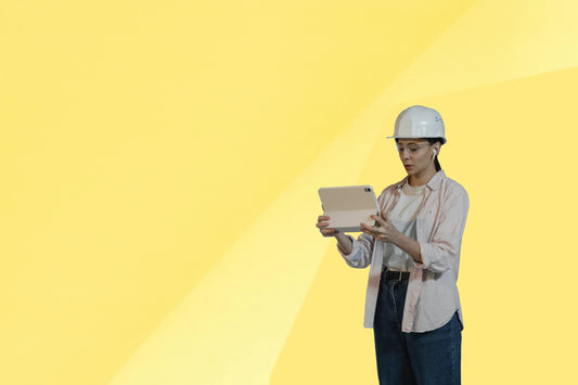 Construction worker in hard hat using tablet against bright yellow background