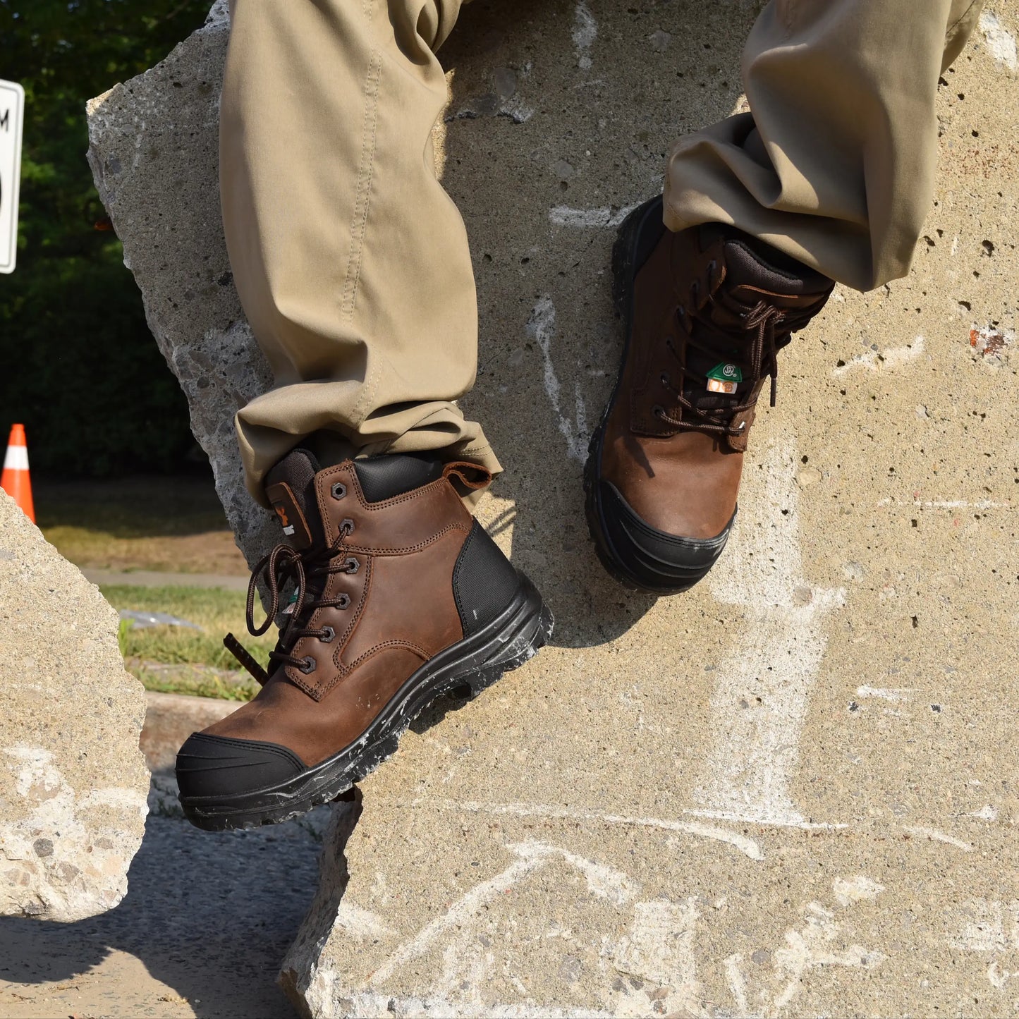 Brown work boots with black soles worn by a person on a concrete surface.